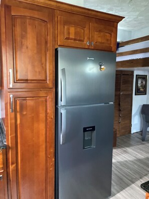 A kitchen with wooden cabinets and a stainless steel refrigerator.