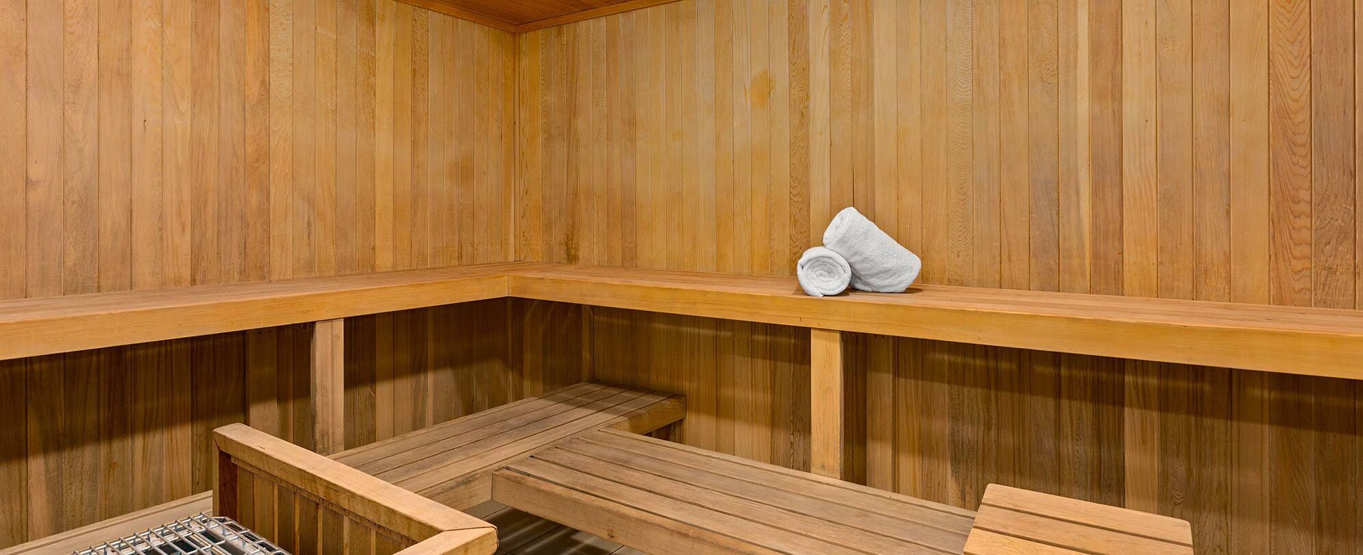 Eine Holzsauna mit Bänken und einem Handtuch auf einem Regal.