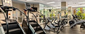 Een fitnessruimte met diverse oefenapparaten, waaronder loopbanden en elliptische trainers.