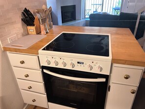 Una cocina con estufa, horno y una encimera con un bloque de cuchillos y saleros.