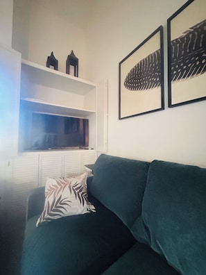 A living room with a green sofa, a zebra-patterned pillow, a flat-screen TV on a stand, and two framed abstract artworks on the wall. - Cozy 1-bedroom loft condo Elkhorn in Sun Valley with gas fireplace and A/C (Sun Valley)