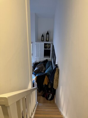 En smal trappe fører op til et rum med en seng, et garderobeskab og en lille hylde med pynteting.