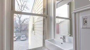 A bathroom with a window, a sink, and a mirror. - Cozy 2BR Apartment  Parking Included (London)