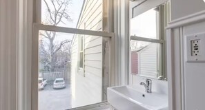 Ein Badezimmer mit Fenster, Waschbecken und Spiegel.