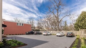 A parking lot with several cars, a red building, and leafless trees. - Cozy 2BR Apartment  Parking Included (London)