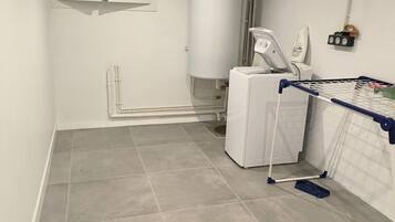 A laundry room with a washing machine, dryer, and ironing station.
