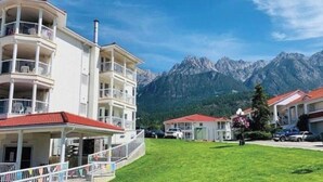 A multi-story building with balconies, a red-tiled roof, and a view of mountains. - SUNCHASER VACATION VILLAS / RIVERSIDE B UNIT / GREAT VIEWS / JUNE 28 - JULY 5 (Fairmont Hot Springs)