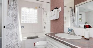 A bathroom with a bathtub, a toilet, a sink, and a large mirror.