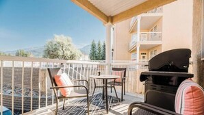 A balcony with a grill, chairs, and a table. - SUNCHASER VACATION VILLAS / RIVERSIDE B UNIT / GREAT VIEWS / JUNE 28 - JULY 5 (Fairmont Hot Springs)