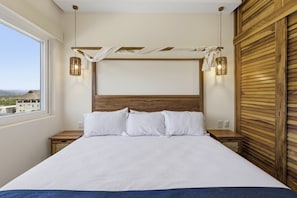 Ein Schlafzimmer mit einem großen Bett, einem Holzkopfende, Nachttischlampen und Blick durch ein Fenster.