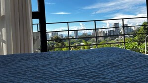 A room with a bed, a view of a cityscape through a window, and a balcony with a railing. - Country House in Quindío Casa Victoria (Calarcá)