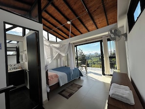 Ein Schlafzimmer mit Bett, Nachttisch, Fenster und Balkon mit Aussicht.