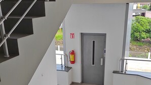 Ein modernes Interieur mit einer Metalltreppe, einem Feuerlöscher und einer Tür.