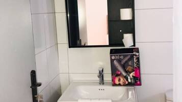 Un baño con lavamanos blanco, un espejo y un perchero para toallas.
