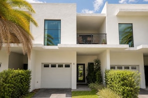 Ein modernes, zweistöckiges Haus mit Garage, Balkon und gepflegtem Garten.