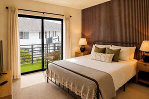 Ein Schlafzimmer mit einem großen Bett, zwei Nachttischen inklusive Lampen, einem Fernseher und einer Glastür, die auf einen Balkon führt.