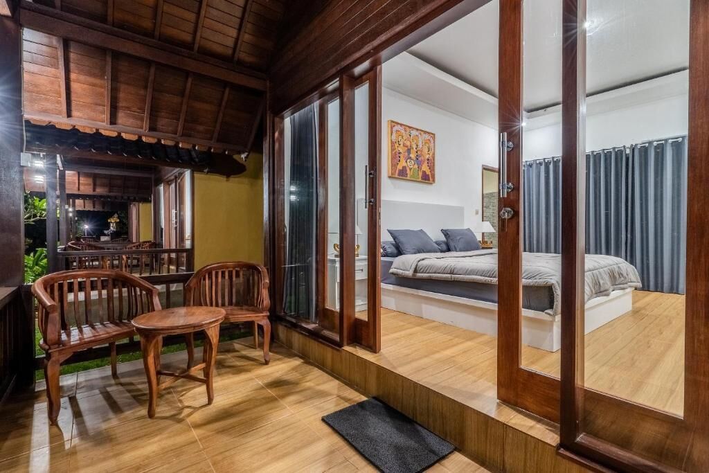 A room with a bed, a sofa, and a dining area with chairs and a table.