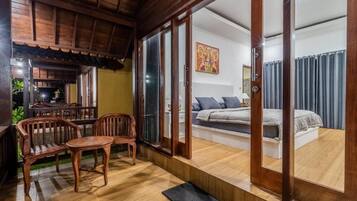 A room with a bed, a sofa, and a dining area with chairs and a table.