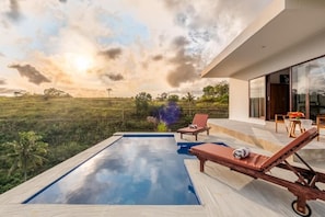 A modern outdoor pool area with lounge chairs and a view of the landscape. - Cozzy Pini Sentana Village Nusa Penida  (Klungkung)