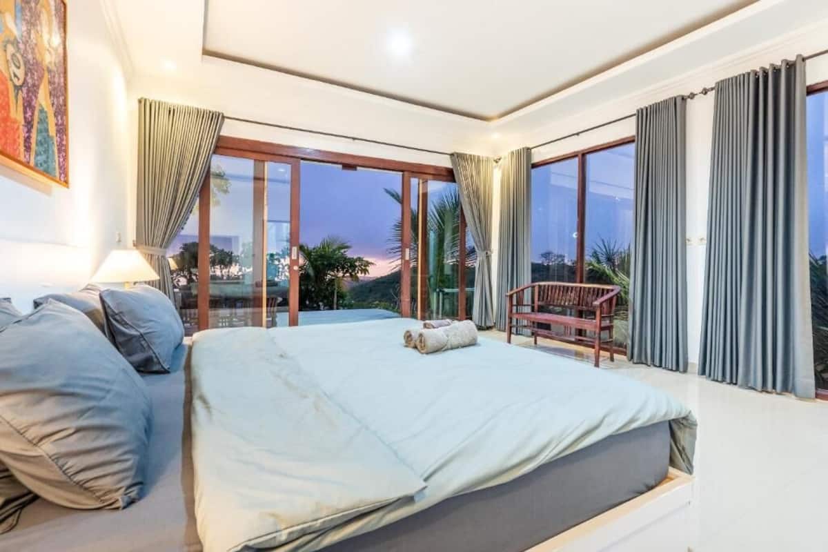 Quarto com cama, uma cadeira e vista para o exterior.