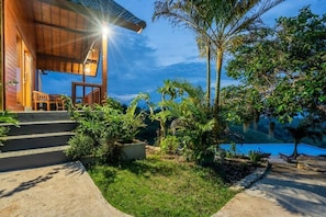A wooden building with a porch, steps leading to the entrance, and a view of a body of water. - Cozzy Pini Sentana Village Nusa Penida  (Klungkung)