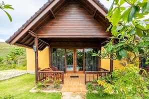 A wooden structure with a covered porch, glass doors, and a small seating area. - Cozzy Pini Sentana Village Nusa Penida  (Klungkung)
