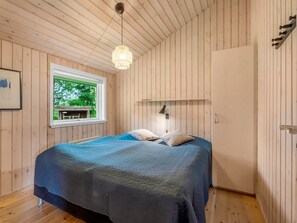 A bedroom with a bed, a window, a hanging light fixture, and a wooden door. - "Sissa" - 700m from the sea by Interhome (Væggerløse)