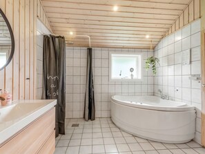 A modern bathroom with a wooden ceiling, a large bathtub, a window with a view, and a mirror. - "Sissa" - 700m from the sea by Interhome (Væggerløse)