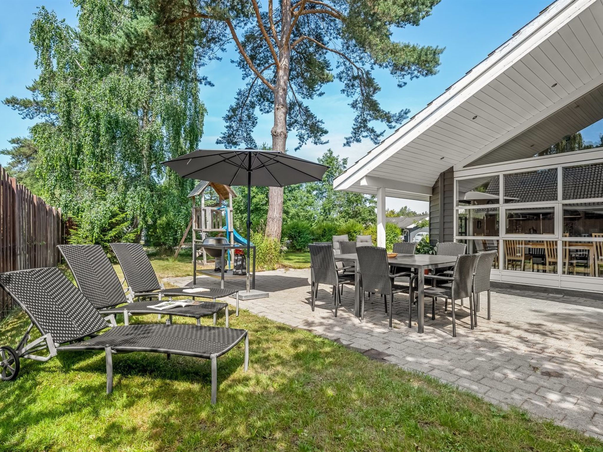 A patio with outdoor furniture, a covered dining area, and a play structure.