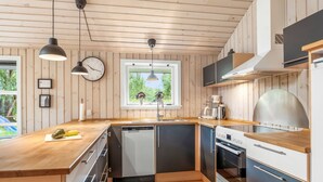 A modern kitchen with wooden cabinetry, a built-in dishwasher, a stove, and pendant lighting. - "Sissa" - 700m from the sea by Interhome (Væggerløse)