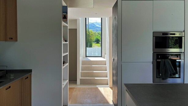 Una cucina moderna con elettrodomestici integrati, una scala che conduce a un balcone e vista sul verde.