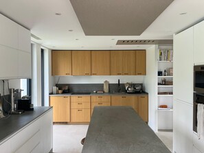 A modern kitchen with wooden cabinets, a central island, and built-in appliances. - Modern house between sea and mountains - Basque Country - Saint-Jean-de-Luz / Ascain (Ascain)