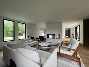 A modern living room with a sofa set, a coffee table, and a TV mounted on the wall. - Modern house between sea and mountains - Basque Country - Saint-Jean-de-Luz / Ascain (Ascain)