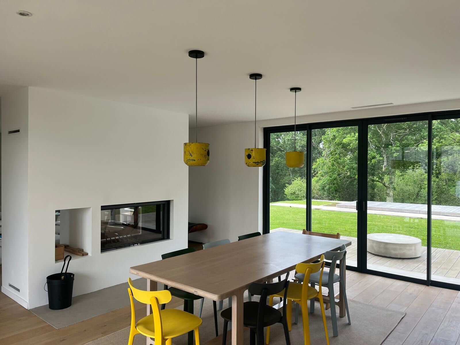 A modern interior with a dining area, large windows, and a view of the outdoors.