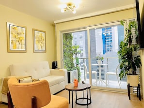 A living room with a sofa, armchair, and a small table with a fan and decorative items. - Executive Apart San Isidro Pool Gym AC (San Isidro)