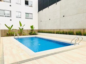 A rectangular swimming pool with a tiled edge, surrounded by a light-colored tiled deck. - Executive Apart San Isidro Pool Gym AC (San Isidro)