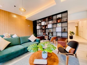 Ein modernes Wohnzimmer mit einem grünen Sofa, einem Holztisch und einem Bücherregal.