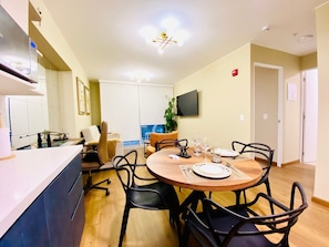 A dining area with a round table, black chairs, a TV mounted on the wall, and a plant in the background. - Executive Apart San Isidro Pool Gym AC (San Isidro)