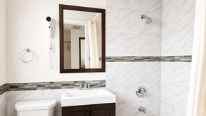 A bathroom with a toilet, sink, vanity, and bathtub. - Budget Inn Ontario (Ontario)