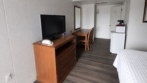 A hotel room with a TV, wooden desk, chair, and a bed. - Budget Inn Ontario (Ontario)