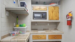 A small kitchenette with a microwave, wooden cabinets, a fire extinguisher, and plastic storage containers. - Spacious Waterfront House w/ boat ramp - sleeps 12 (Bay St. Louis)