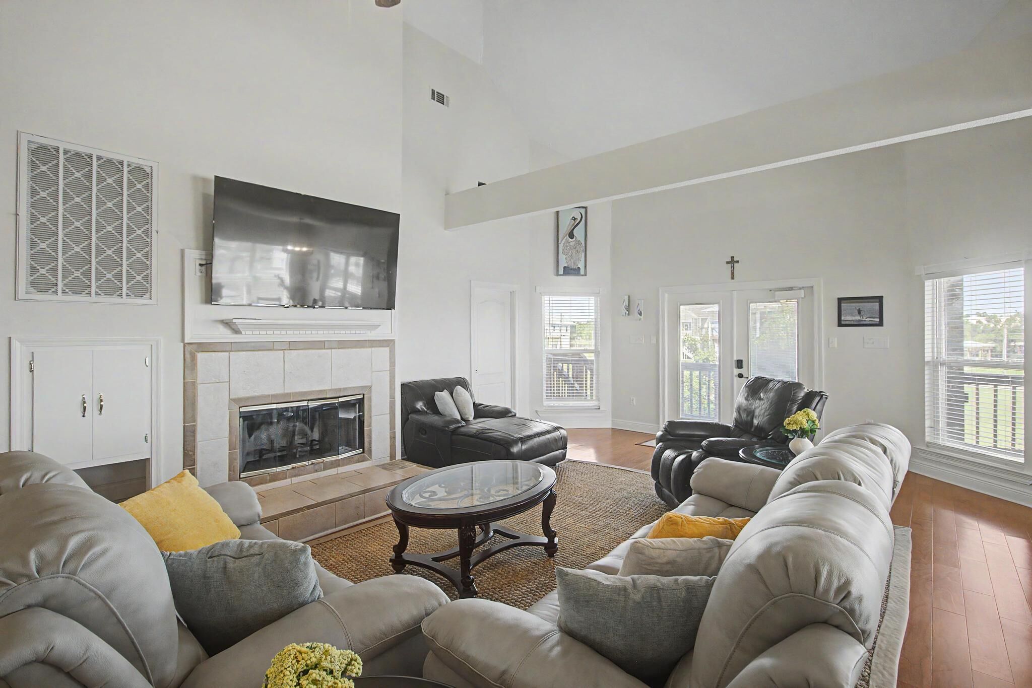 A spacious living room with a fireplace, leather sofas, a flat-screen TV, and a large window.