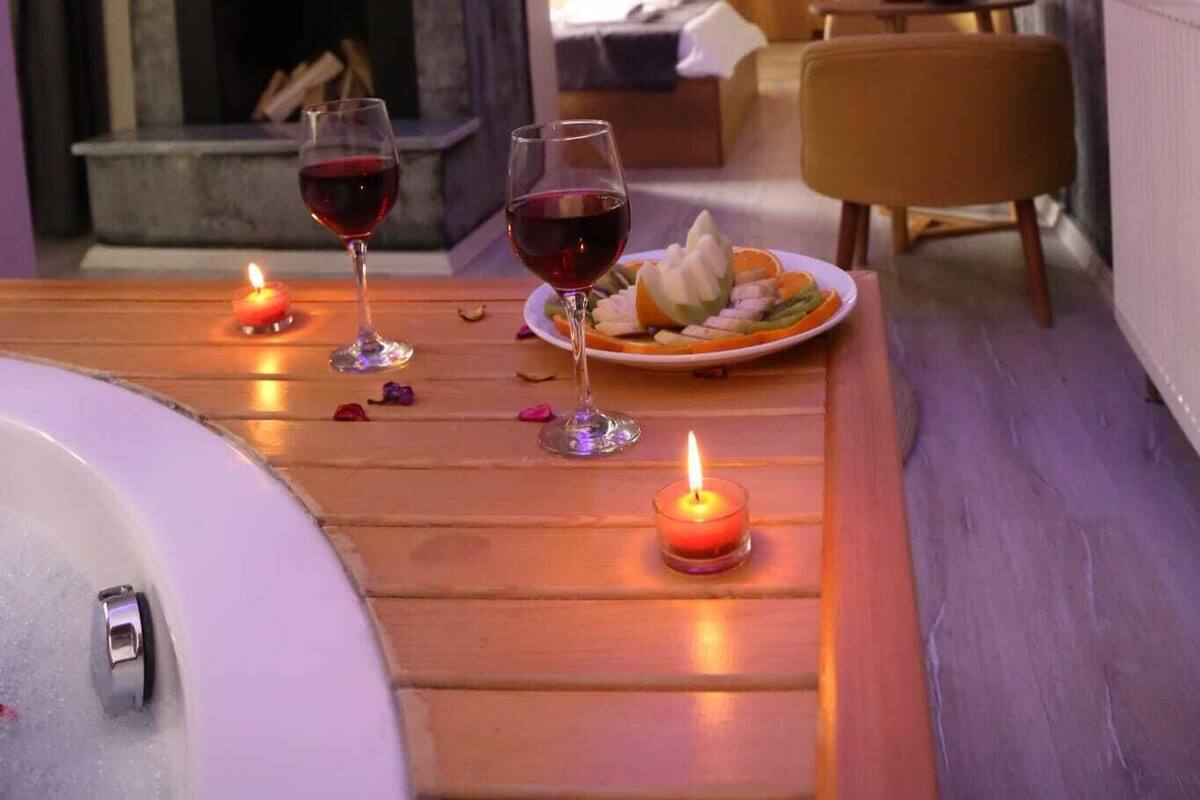 A cozy room with a fireplace, a dining table with candles, and a bed in the background.
