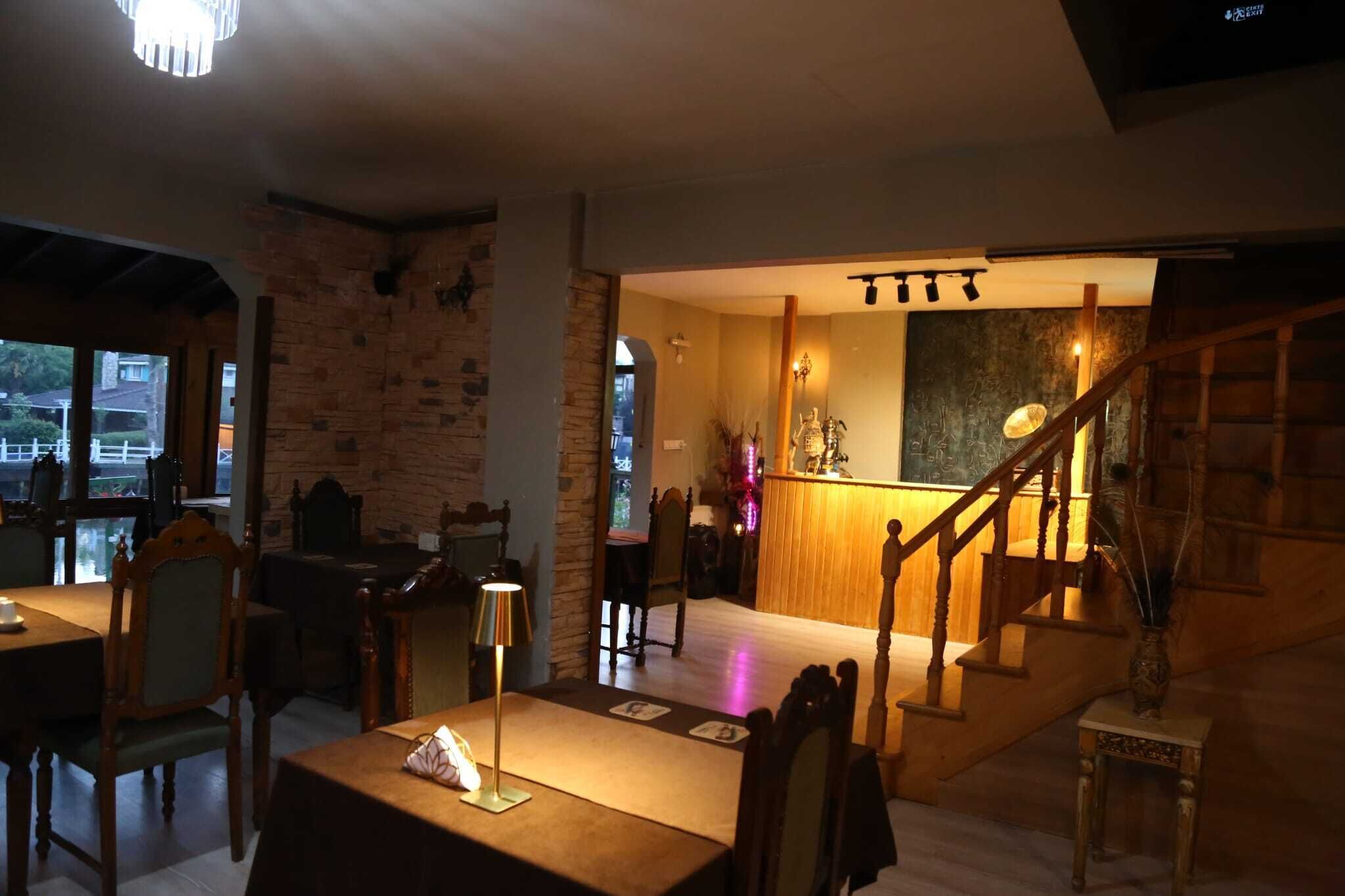 A restaurant with wooden furniture, a staircase, and a view of the outside.