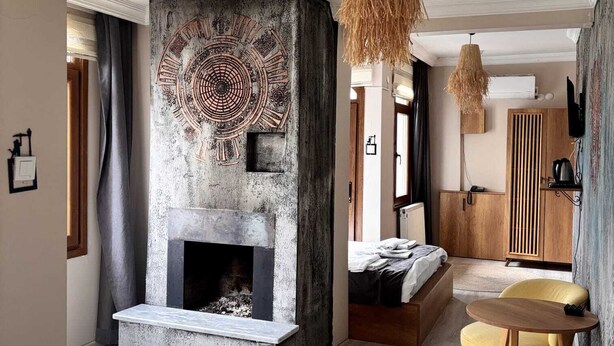 Una sala de estar moderna con chimenea, un comedor con sillas amarillas y un ventanal grande.