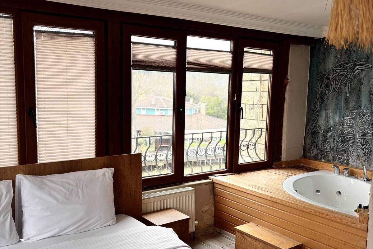 A hotel room with a large bed, a wooden bathtub, and a view of the outside.