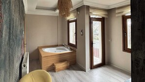 Una habitación amplia con una bañera grande, una mesa de madera y una lámpara colgante.