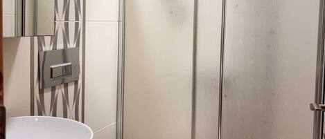 A bathroom with a white sink, toilet, and a glass-enclosed shower area.