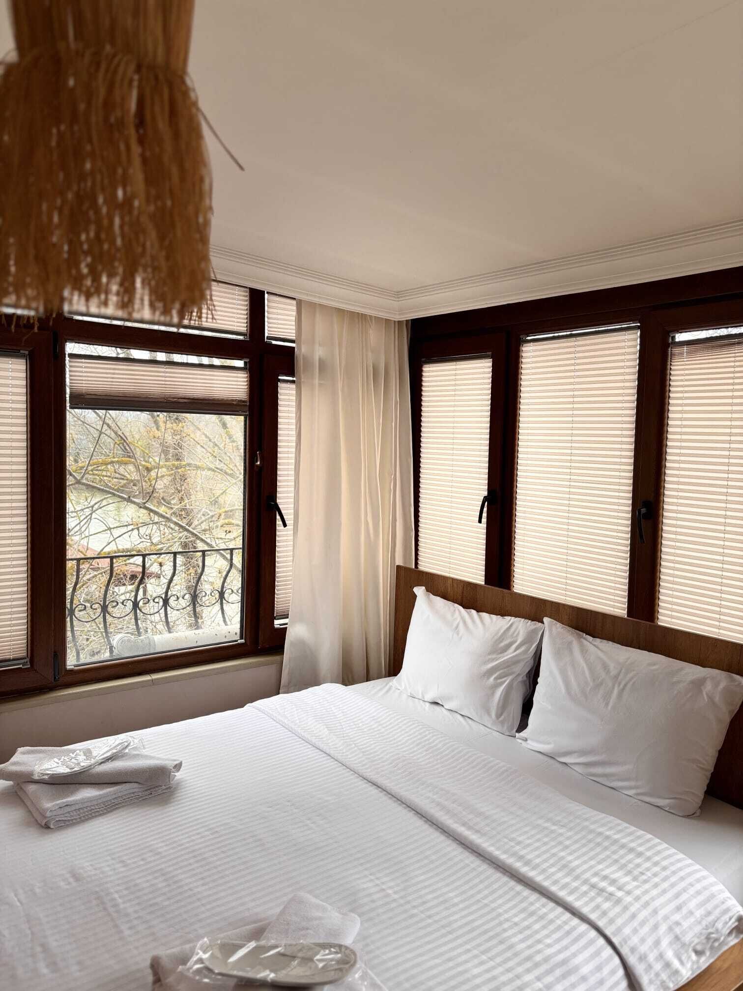 Una habitación de hotel con una cama grande, una ventana con persianas, una cortina y una lámpara colgante.