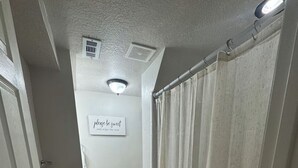 A hallway with a wooden floor, a brown rug, a white door, a white curtain, and a sign on the wall.